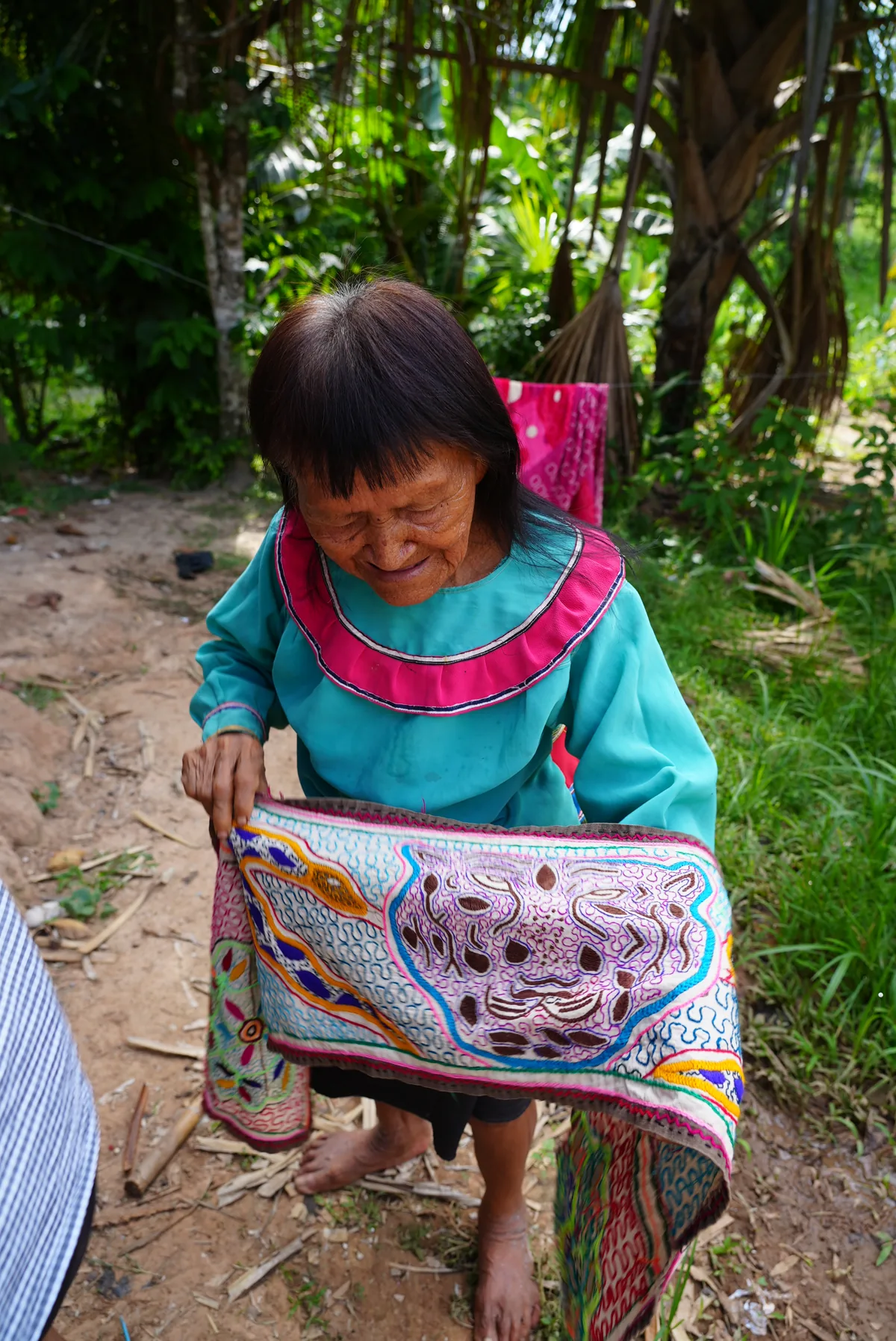 A Shipibo elder holding an embroidered textile in the Amazon