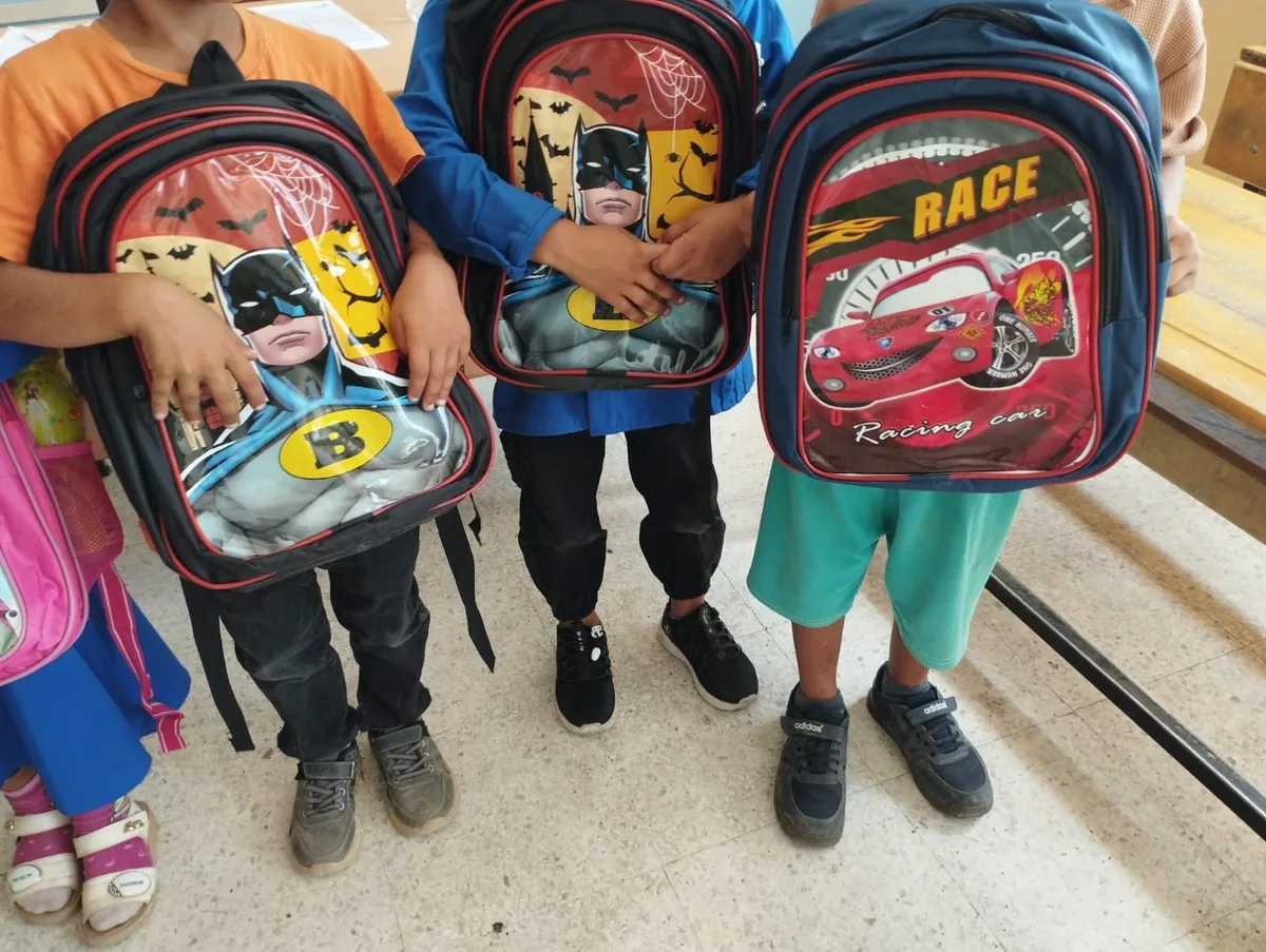 Village children holding new school backpacks during a Community Garden distribution near Şanlıurfa