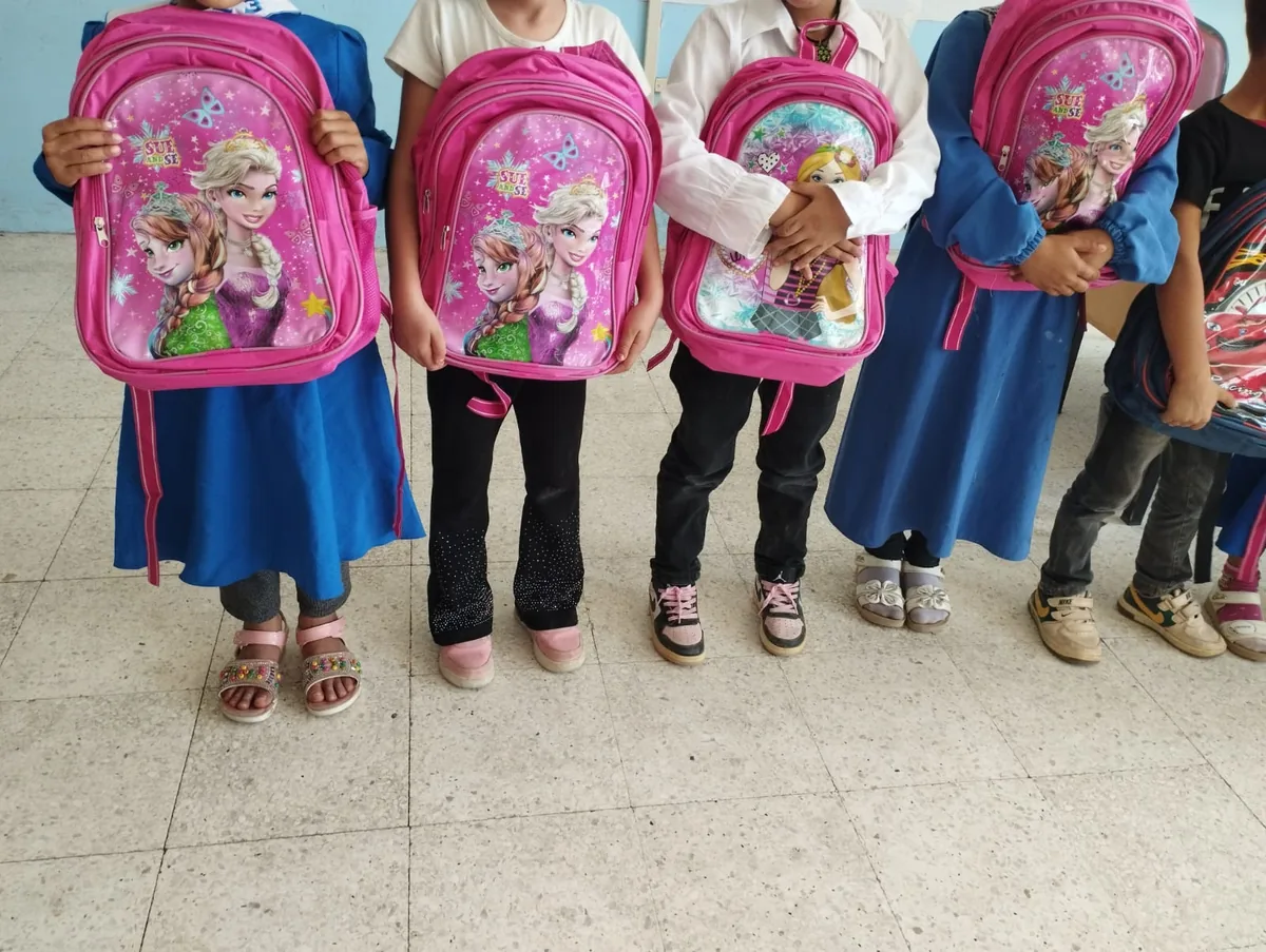Village children holding new school backpacks during a Community Garden distribution near Şanlıurfa